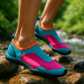 Woman wearing best water shoes for women stepping on wet stones near clear stream outdoors