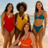 diverse women wearing best swimsuits for women confidently on sunny beach with waves and sand background